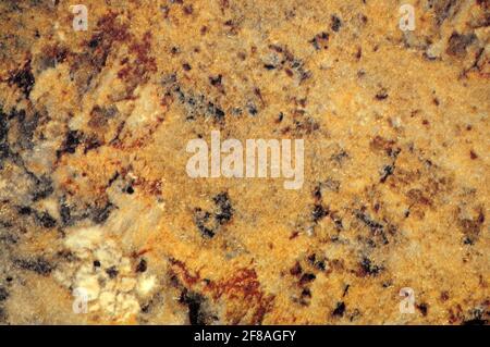 Hellbraunes Headset, eine flache Oberfläche aus Naturstein mit dunklen und hellen Flecken in Nahaufnahme. Hintergrund, Muster, Textur. Stockfoto