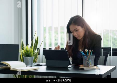 Geschäftsfrau, die mit einem Eingabestift auf einem digitalen Tablet mit einem Laptop in einem modernen Büro arbeitet. Stockfoto