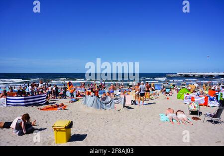 KOLOBRZEG, POLEN - 16. Jul 2015: Viele Menschen sitzen und liegen an einem sonnigen Tag auf Sand am Strand Stockfoto