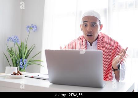 Verwirren asiatische muslimische Geschäftsmann mit Laptop Stockfoto