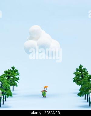 Clown Figur hält einen Regenschirm, der zusammen mit Bäumen läuft, die isoliert sind Blauer Hintergrund Stockfoto