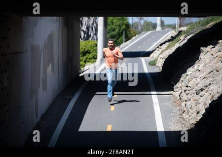 Voller gesunder Mann läuft und sprintet im Freien. Junger Fitnesssport männlicher Läufer läuft auf der Stadtstraße. Stockfoto