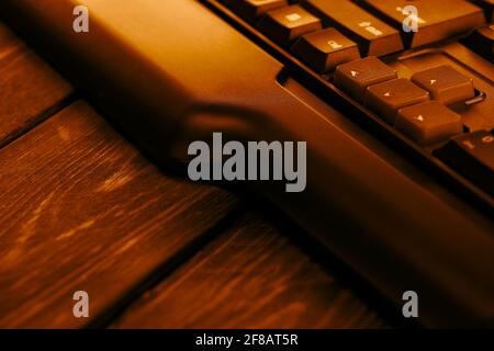 Gaming-Computer-Tastatur auf einem Holztisch. Nach-oben- und nach-unten-Tasten auf einer Computertastatur. Stockfoto