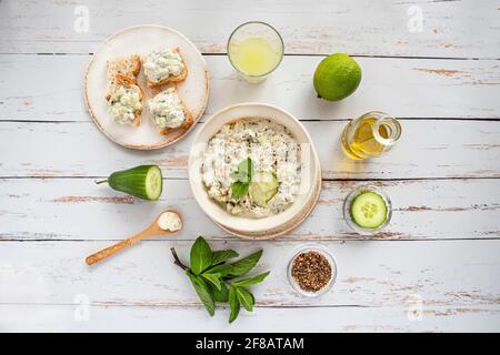 Zubereitung von mediterranem Zatziki mit Joghurt, Gurke, Minze und anderen Zutaten Stockfoto