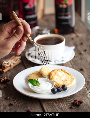 Russische Hüttenkäse-Pfannkuchen mit saurer Rahm Stockfoto
