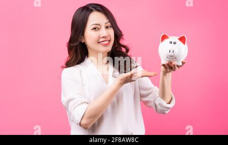 Asiatische Geschäftsfrau hält Schweinchen in der Hand, Geld sparen Konzept Stockfoto