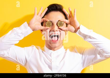 Asiatischer Geschäftsmann hält Bitcoin in der Hand und hat ein glückliches Gesicht Stockfoto