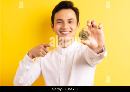 Asiatischer Geschäftsmann hält Bitcoin in der Hand und hat ein glückliches Gesicht Stockfoto