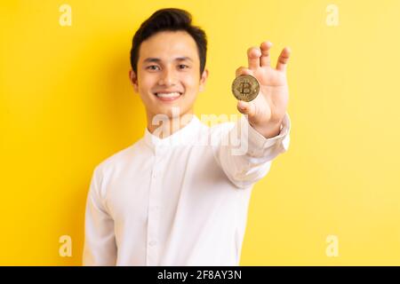 Asiatischer Geschäftsmann hält Bitcoin in der Hand und hat ein glückliches Gesicht Stockfoto