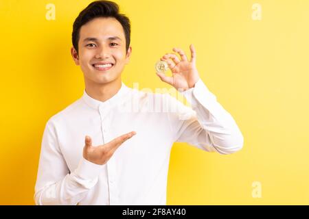 Asiatischer Geschäftsmann hält Bitcoin in der Hand und hat ein glückliches Gesicht Stockfoto