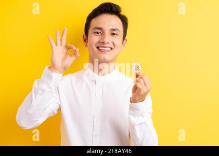 Asiatischer Geschäftsmann hält Bitcoin in der Hand und hat ein glückliches Gesicht Stockfoto