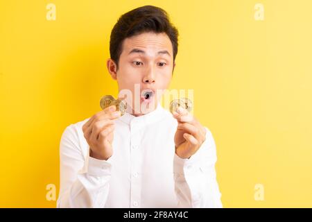 Asiatischer Geschäftsmann hält Bitcoin in der Hand und hat ein glückliches Gesicht Stockfoto