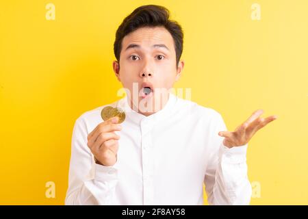 Asiatischer Geschäftsmann hält Bitcoin in der Hand und hat ein glückliches Gesicht Stockfoto