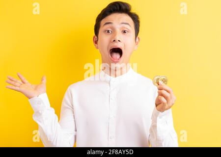 Asiatischer Geschäftsmann hält Bitcoin in der Hand und hat ein glückliches Gesicht Stockfoto