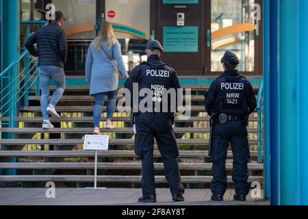 Bielefeld, Deutschland. April 2021. Polizeibeamte stehen vor dem Eingang zum Bezirksgericht. Dies markiert den Beginn des Prozesses über einen Kampf vor einer Diskothek unter besonderen Sicherheitsmaßnahmen. Fünf Männer zwischen 28 und 40 Jahren werden angeklagt. Die Staatsanwaltschaft wirft den Mitgliedern einer Großfamilie besonders schwere Verletzungen des Friedens vor. Zusätzlich zu den Fisticuffs und Kicks wurden mehrere Schüsse abgefeuert. Bis Januar 2023 hat das Amtsgericht mehr als 60 Termine festgelegt. Quelle: Friso Gentsch/dpa/Alamy Live News Stockfoto