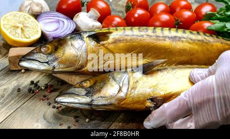 Köstliche geräucherte Fischmakrele auf einem Holztisch neben den Kirschtomaten, Zwiebeln, Pilzen und Petersilie. Gesunde mediterrane Küche Rezept. Schließen-U Stockfoto