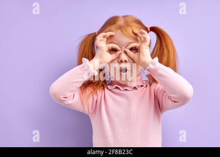 Portrait von überrascht niedlichen kleinen Mädchen Kind stehend isoliert über lila Hintergrund, kopieren Raum. Kinder, menschliche Emotionen Konzept Stockfoto