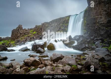 Oxararfoss Wasserfall in Dingvellir, Island. Langzeitbelichtung eines wunderschönen isländischen Wasserfalls an einem kalten und bewölkten Tag. Grenze der tektonischen Platte. Stockfoto