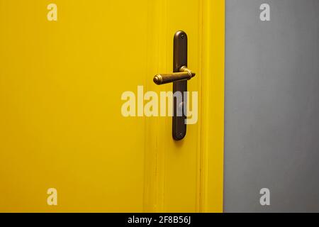 Nahaufnahme der gelben Tür mit Vintage-Türknopf. Stockfoto
