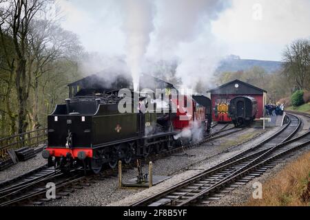 Historische Dampfzüge oder Loks, die Rauchwolken aufblähen (Motorfahrer im Taxi & Enthusiasten beobachten) - Oxenhope Station Sidings, Yorkshire, England Stockfoto