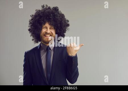 Flippiger Geschäftsmann mit Haarperücke und Daumen nach oben Bei grauem Kopierbereich Stockfoto