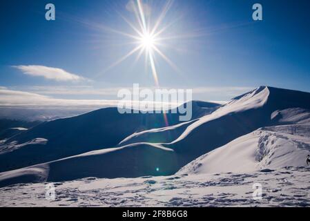 Verschneite Berge in der Sonne Morgen. Toller Blick über einige Bergketten und Gipfel in einer atemberaubenden Schneelandschaft. Stockfoto