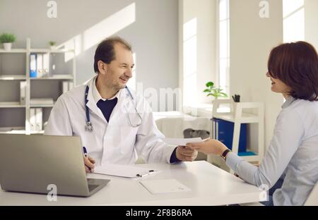 Freundlich lächelnder Arzt, der dem Patienten in der medizinischen Klinik ein Rezept gibt Büro Stockfoto