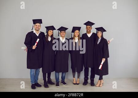 Porträt einer Gruppe erfolgreicher Absolventen verschiedener Nationalitäten mit Diplomen in den Händen. Stockfoto