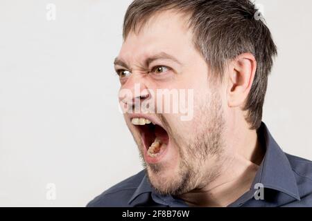 Ein wütender wütender Mann schreit mit offenem Mund auf weißem Hintergrund, um den Platz für Text zu kopieren. Stockfoto