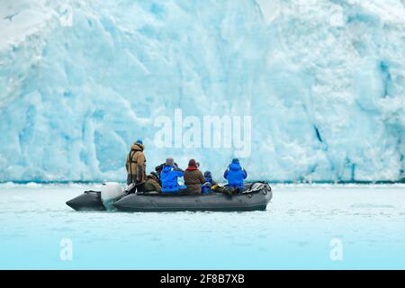 Naturliebhaber in Arctic Svalbard, Norwegen. Motorboot mit Touristen auf dem Eismeer mit Gletscher. Arktische Kreuzfahrt im Winter, schwarzes Motorboot mit Photograp Stockfoto