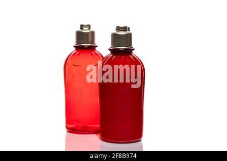 Rote Flaschen für Duschgel und Creme auf weißem Hintergrund. Leichte Kunststoffgläser. Auf weißem Hintergrund. Harte Schatten. Isoliert. Geschenkkonzept. Stockfoto