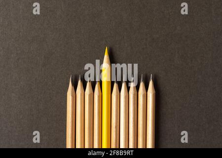 Ein gelber Bleistift, der aus der Serie der grauen Bleistifte heraussticht. Stockfoto