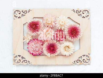 Rustikale Hochzeitseinladung im Retro-Stil mit Blumenmuster auf Holzrahmen auf hellem Hintergrund. Stockfoto