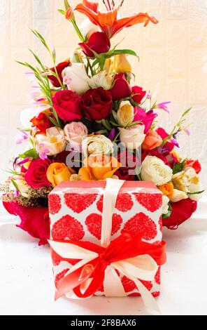 Blumenstrauß mit einer Geschenkbox in Herzen auf weißem Hintergrund. Ein großer Strauß gemischter Blumen und Rosen. Die Zusammensetzung eines professionellen Floristen. Stockfoto