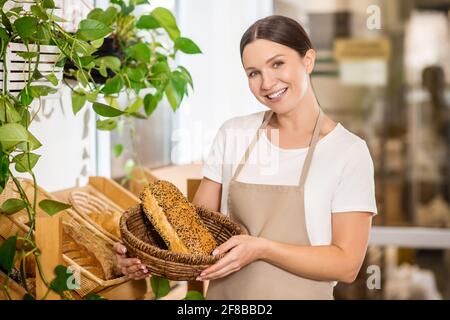 Frau in Schürze mit Korb mit Brot Stockfoto