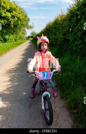Unglückliches 8-jähriges Mädchen, das einen Raskullz-Einhorn-Fahrradhelm waring Stockfoto