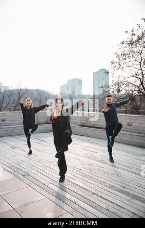 Der Meister des Tai Chi steht mit zwei Schülern auf einem Bein Stockfoto
