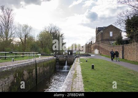 Ein Paar, das den Treidelpfad entlang des Grand Union Canal in der Nähe von Hanwell im Westen Londons, Großbritannien, spazierengeht Stockfoto