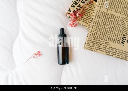 Leere Serumflasche aus bernsteinfarbenem Glas auf weißem Hintergrund. Naturkosmetik, alternative Medizin, Minimalkonzept. Draufsicht. Stockfoto