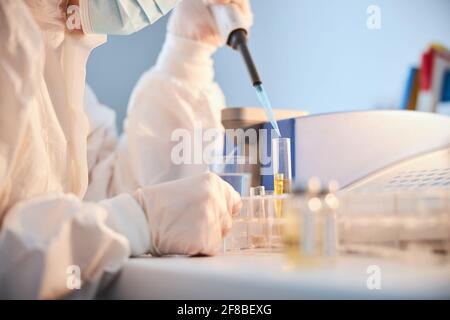 Frau in einer Gesichtsmaske, die eine chemische Analyse durchführt Stockfoto