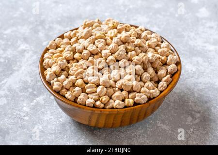 Trockene Kichererbsen in Holzschüssel auf Betongrund gesundes Essen, pflanzliches Protein-Konzept Draufsicht Flat Lay. Stockfoto