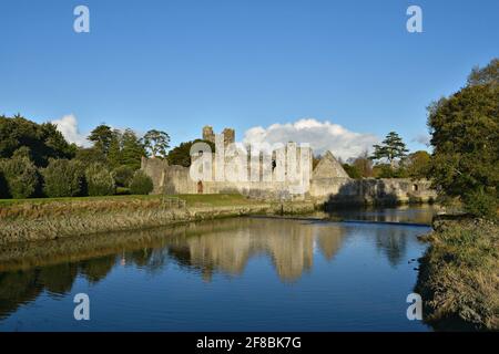 Landschaft mit Panoramablick auf die mittelalterliche Festung Desmond Castle und die umliegenden Gärten am Ufer des Flusses Maigue in Adare, Limerick, Irland. Stockfoto
