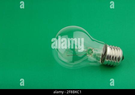 Elektrische Glühbirne auf grünem Hintergrund. Ausschalten. Konzept der drahtlosen Kraftübertragung. Kreative Krise Müdigkeit mentalen Stress. Stockfoto