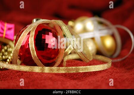 Weihnachtsbaumkugel und goldenes Band auf dem Hintergrund der Weihnachtsdekoration. Neujahrs- oder Weihnachtskarte. Stockfoto