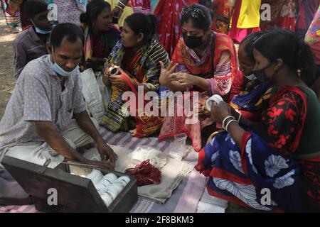 Naogaon, Bangladesch. April 2021. Frauen überprüfen Shakha Pola auf einem Dorffest, während sie das Poush Sankranti Festival in der Nähe von Kashipur im Naogaon Distrikt, nördlich von Bangladesch, feiern. Poush Sankranti ist auch als Makar Sankranti bekannt, die am letzten Tag des bengalischen Poushmonats gefeiert wird. Quelle: MD Mehedi Hasan/ZUMA Wire/Alamy Live News Stockfoto