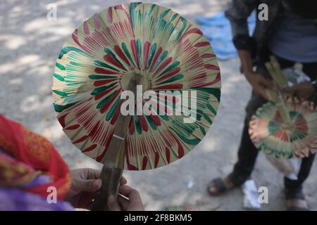 Naogaon, Bangladesch. April 2021. Ein Käufer überprüft einen Palmblatt-Fan auf einer Dorfmesse, um das Poush Sankranti-Festival in der Nähe von Kashipur im Naogaon-Distrikt, nördlich von Bangladesch, zu feiern. Poush Sankranti ist auch als Makar Sankranti bekannt, die am letzten Tag des bengalischen Poushmonats gefeiert wird. Quelle: MD Mehedi Hasan/ZUMA Wire/Alamy Live News Stockfoto