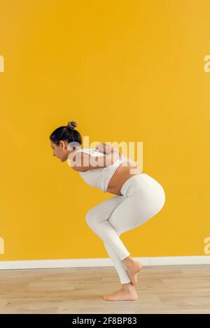 Nahaufnahme einer jungen Frau, die sich hinter ihrem Rücken die Hände anschließt, während sie Yoga-Übungen macht. Junge attraktive Yogi-Frau, die Yoga praktiziert und Namaste hinter sich lässt Stockfoto