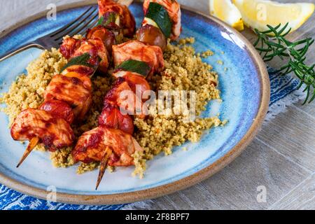 Würzige Hähnchen-, Tomaten- und Zucchini-Spieße mit Couscous Stockfoto