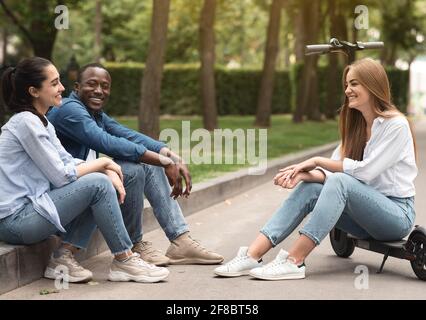 Drei verschiedene Freunde verbringen Zeit im Park und reden Stockfoto