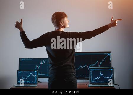 Erfolgreicher männlicher Trader, der den Monitor mit einem Börsendiagramm betrachtet Oder Diagramm Stockfoto